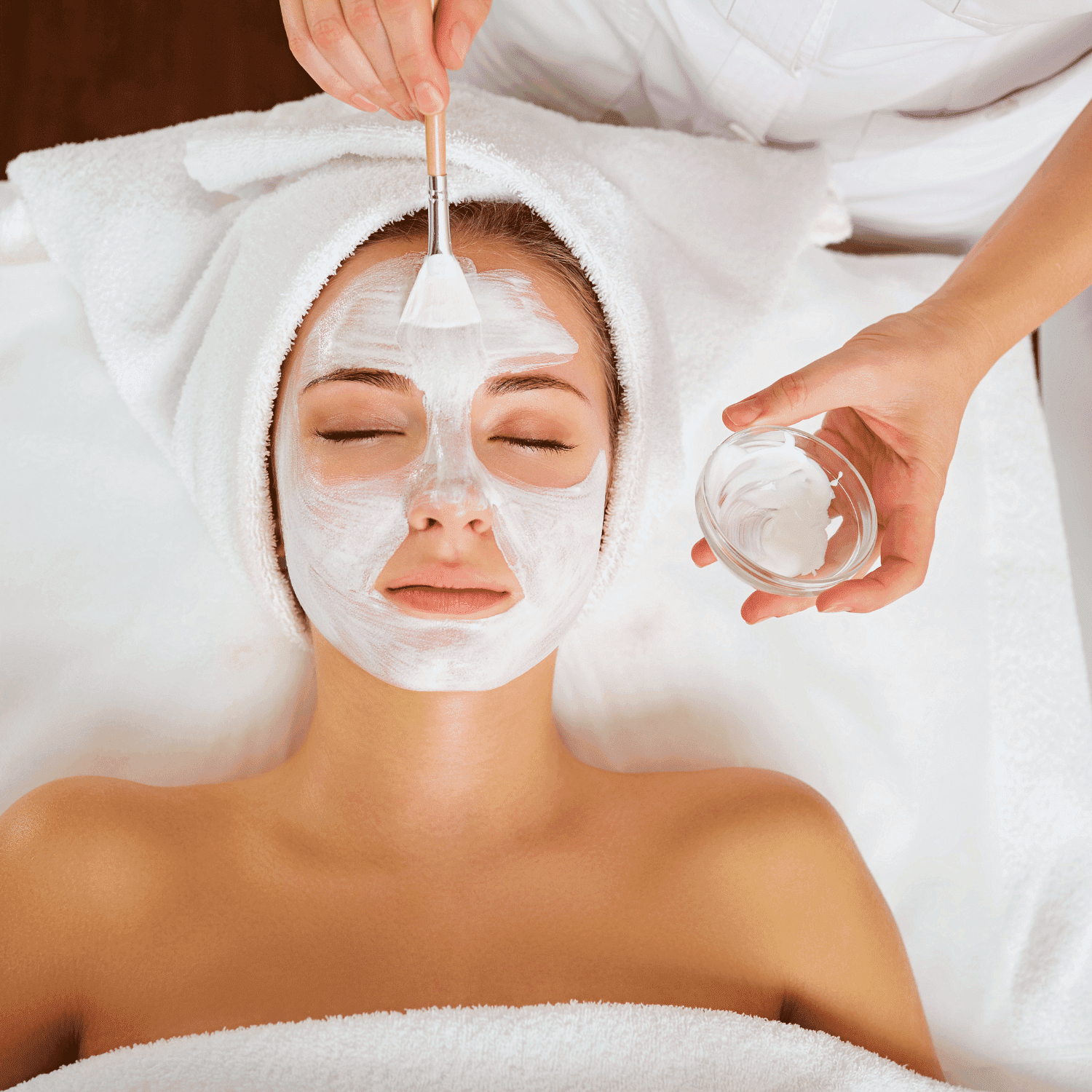 Woman receiving facial mask treatment at spa.
